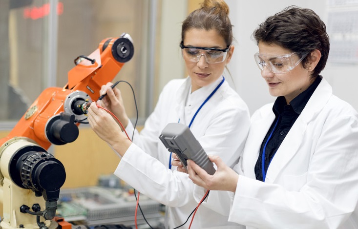 Female engineers inspecting electronic machine