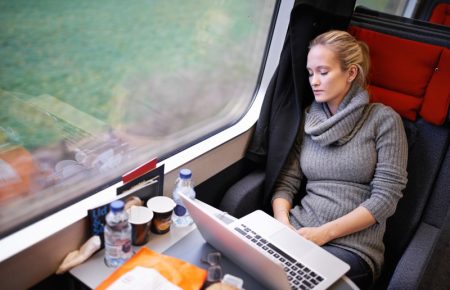 Picture of young professional women travelling on the train asleep with laptop open on the table