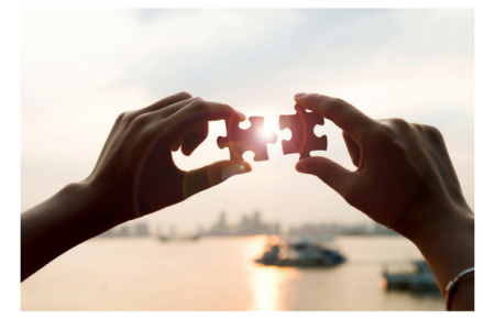 Image of two hands holding matching jigsaw puzzles into the sunset, signifying future plans.